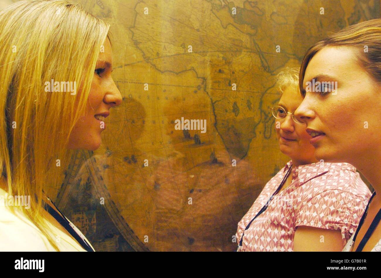 Sally Kettle (right), 27, from Northampton, talks to Claire Mills (left), 22, from Dunstable and Ali Boreham, 34, from Ingworth in Norfolk, in front of a world map inside the Royal Geographical Society in London, Wednesday August 18, 2004, as they discuss the challenges awaiting them of a rowing race across the Atlantic Ocean. The three women will be joined by Diane Parks, 44, as they begin training for next year's Atlantic Rowing Race between the Canary Islands and Barbados, with a total mileage of 2,900 nautical miles. Stock Photo