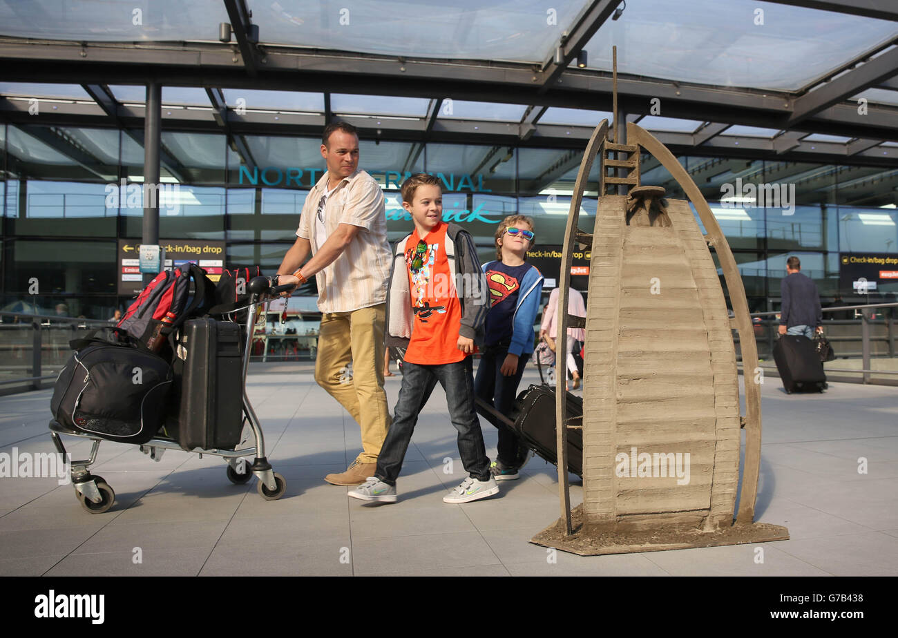(Left to right) Dale Anderton, and sons Andrew, aged 10, and James, seven, from Eastbourne, look at a sand sculpture of Dubai's Burj Al Arab, created by Zeus, at London Gatwick Airport to celebrate the airport's expanded route network. Stock Photo