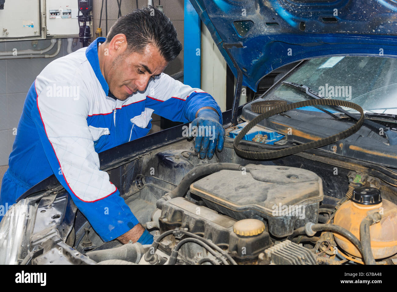Automotive specialist adjusting an engine in his garage, closeup of an