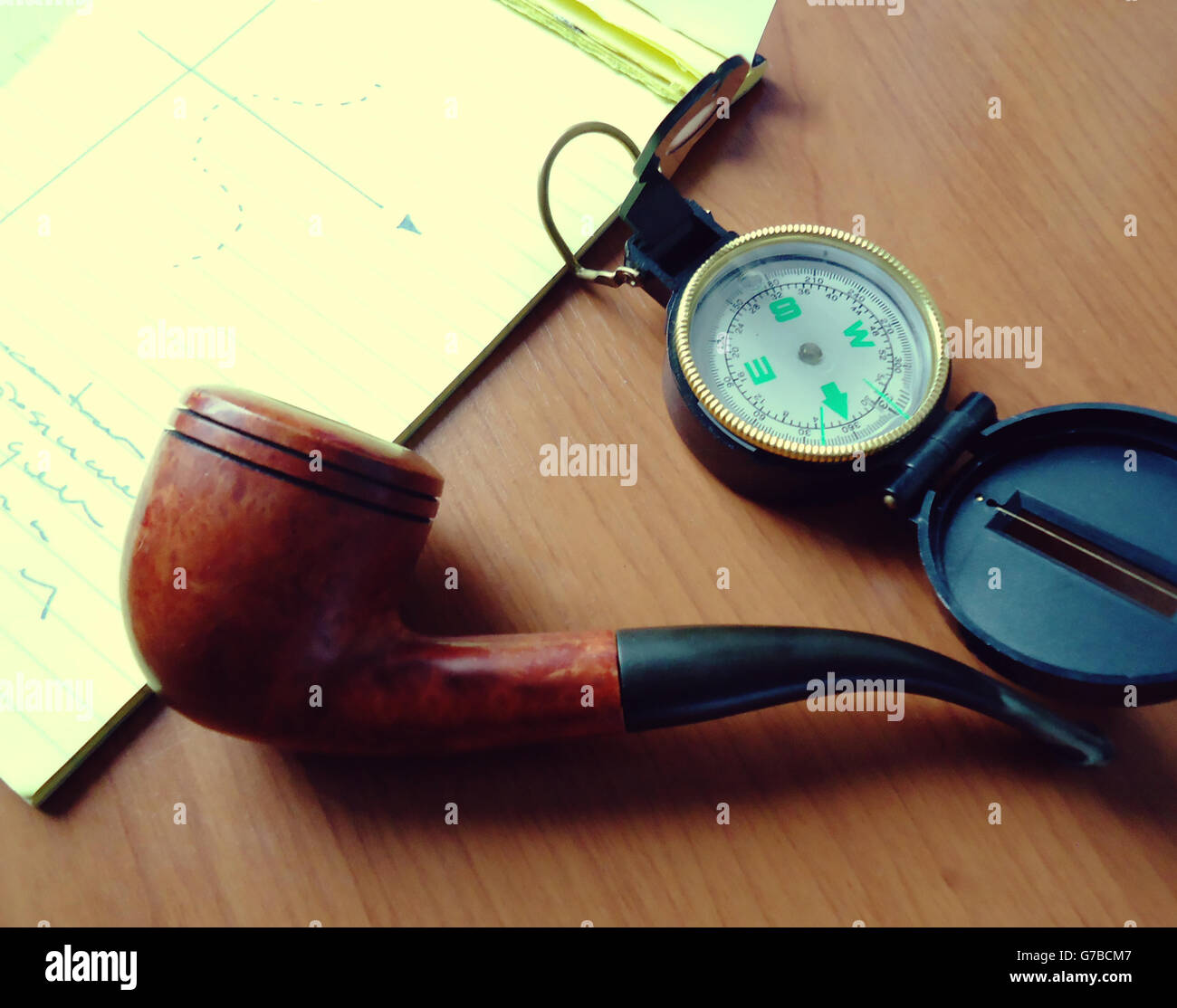 Photograph of a pipe and a compass on a wood table Stock Photo