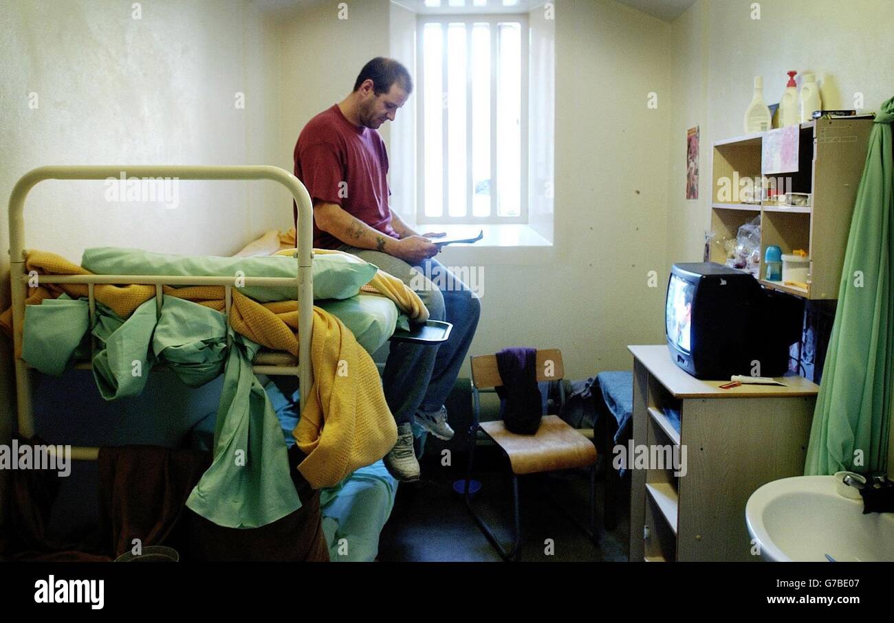An inmate reads in his cell at Wandsworth Prison in London. Conditions at a jail much-criticised by the Chief Inspector of Prisons 16 months ago have deteriorated, according to a new report. Wandsworth prison in south London was holding inmates in even more cramped conditions due to the ever-rising prison population, said the study. Stock Photo