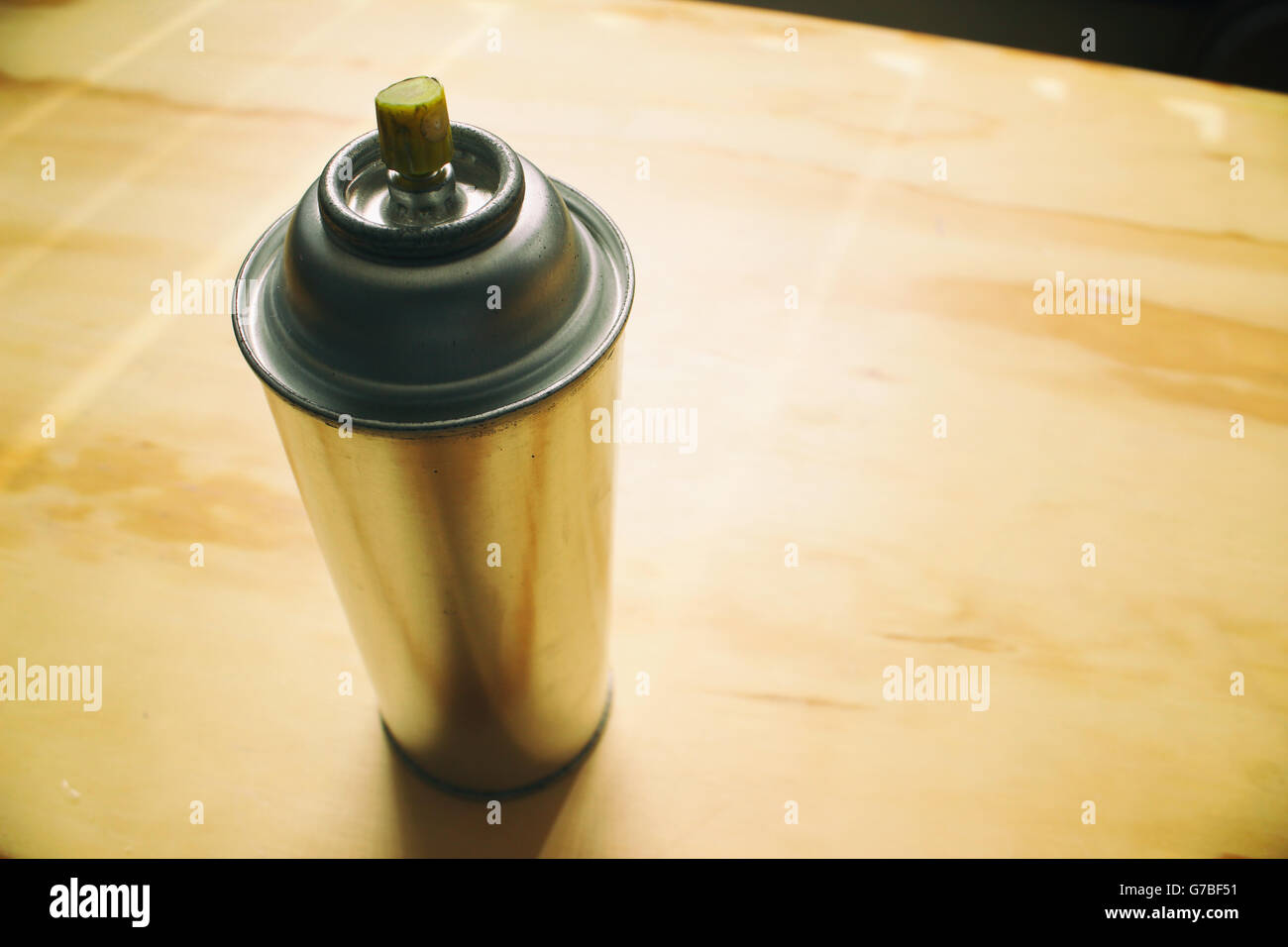 Photograph of a spray paint can on a wood table Stock Photo
