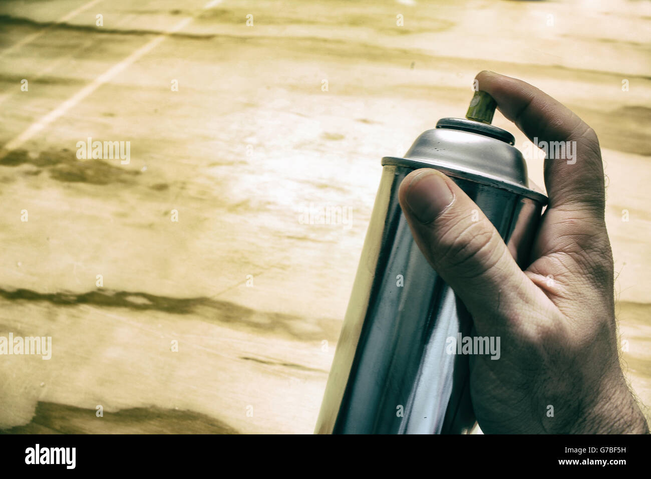 Photograph of a spray paint can and a human hand on a wood table Stock Photo