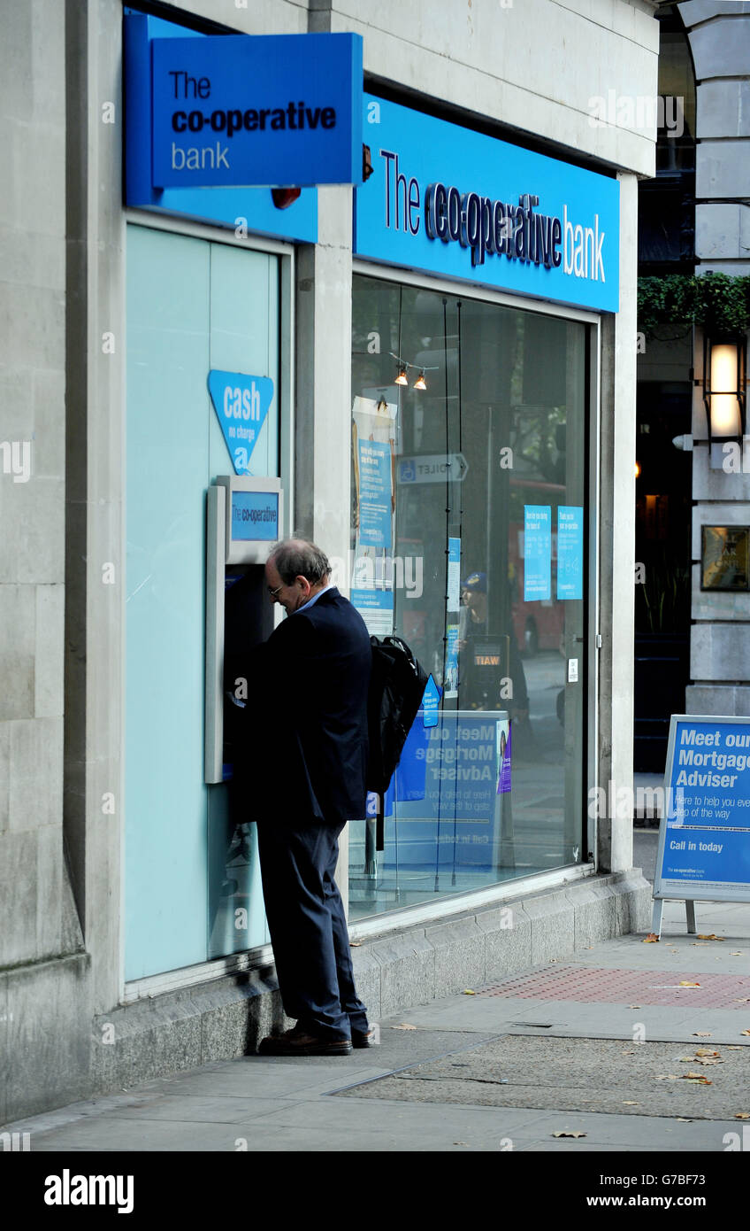 Stock photo of a man using a cash dispenser at a co-operative bank in Holborn, central London. Stock Photo
