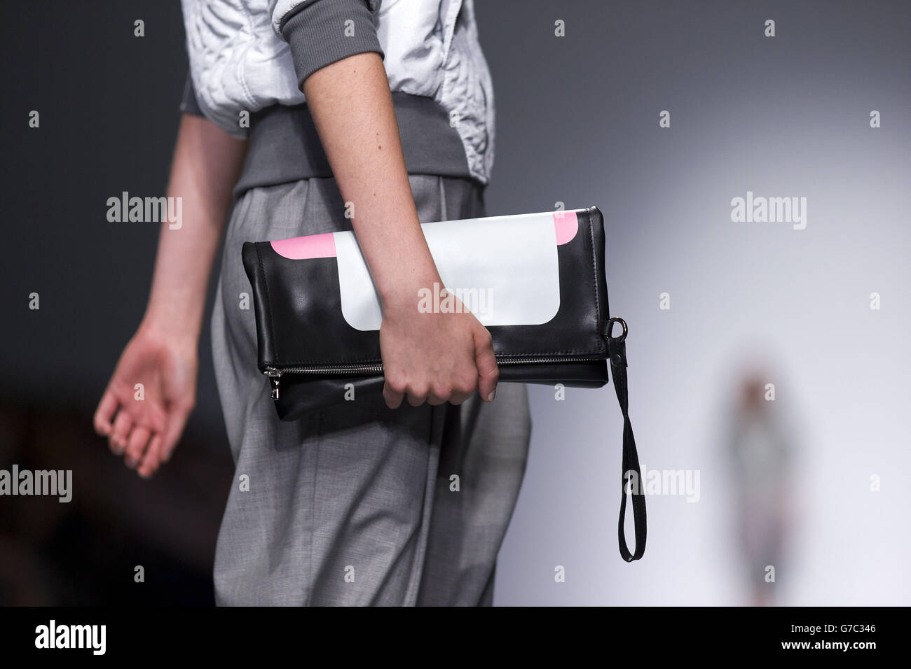 A model holds a clutch bag on the catwalk during the Christopher Raeburn catwalk show at Somerset House in London during London Fashion Week. Stock Photo