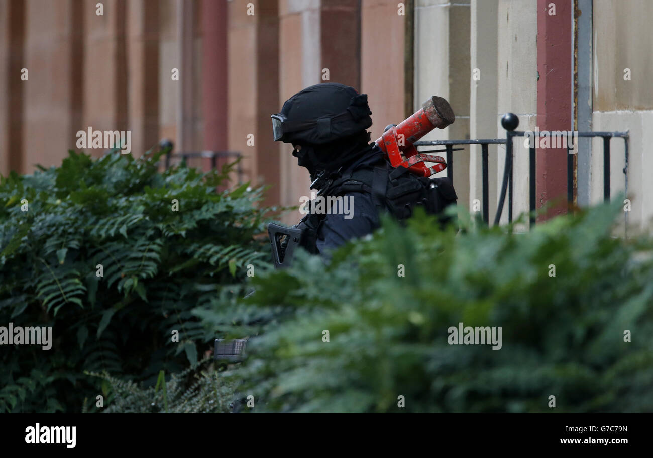 An armed police officer leaves the scene in Boyd Street in the Crosshill area of Glasgow, after police were called to an incident. Stock Photo