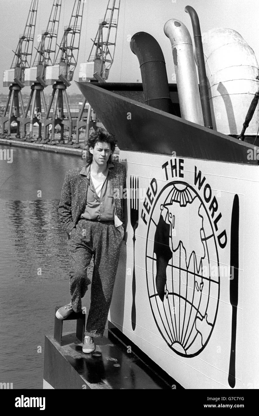 Pop star Bob Geldof stands on the ship, Band Aid I, by a funnel painted with a poignant message at Tilbury docks before the ship sailed with its cargo of relief supplies for famine-stricken Ethiopia. Stock Photo