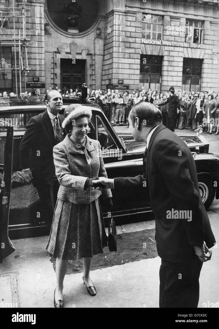 Queen Elizabeth II is greeted by Sir Max Aitken, director and chairman of Beaverbrook Newspapers Limited, on her arrival at the Daily Express building. In the background is the Press Association/Reuters building. Stock Photo