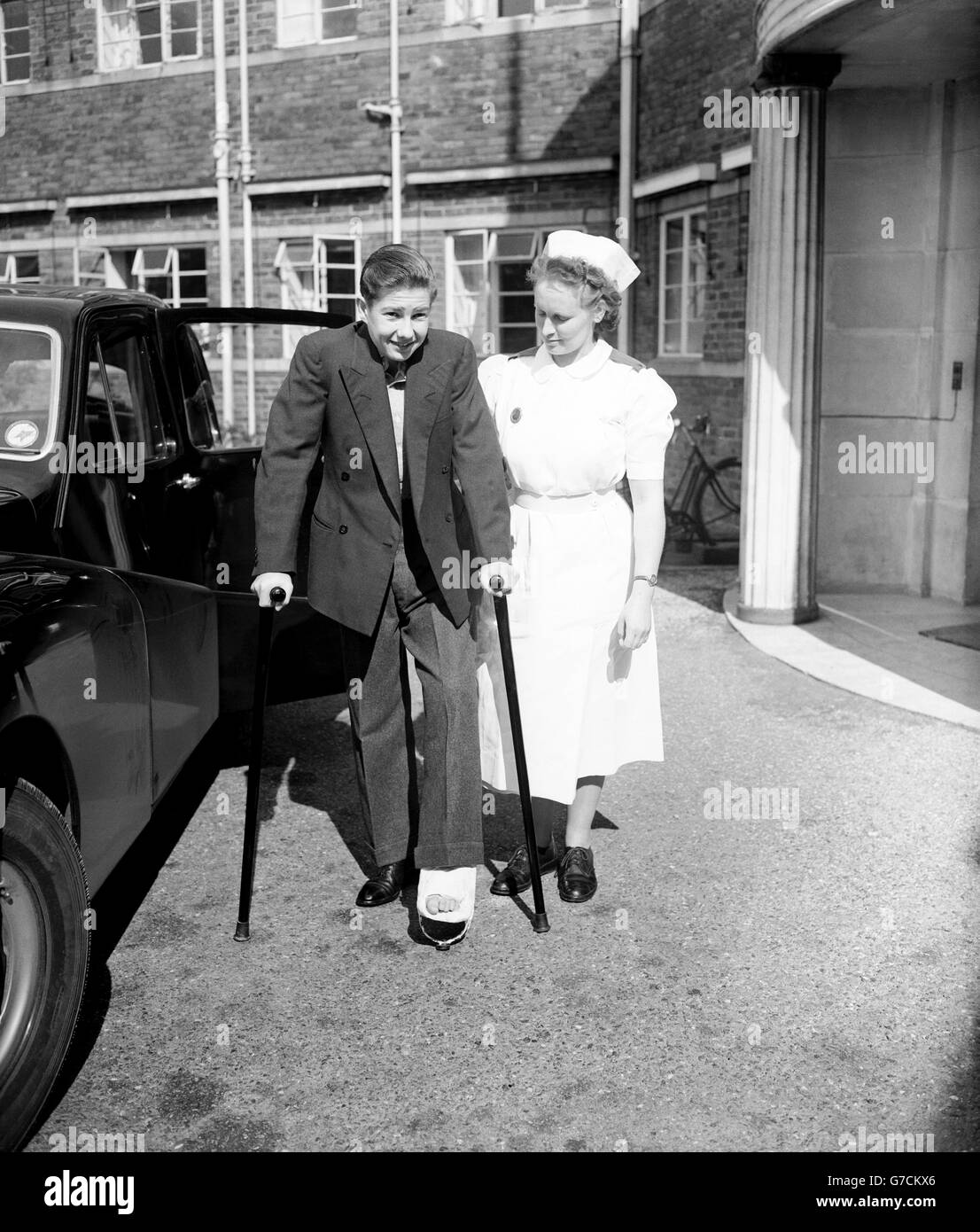 Boy jockey Lester Piggott leaving Queen Victoria Hospital with the aide of nurse A. Steel on crutches after breaking his leg in a fall at Lingfield Park. Stock Photo