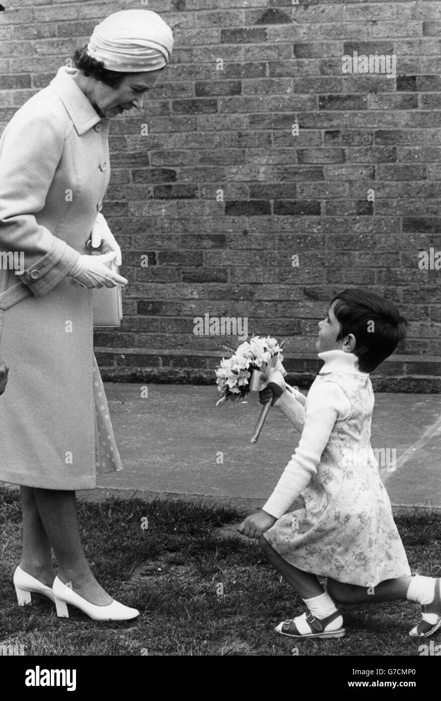 Queen Elizabeth II is given flowers by Heidi Cornwall, 5, at Hewett School in Norwich during her Silver Jubilee visit to Norfolk. Stock Photo