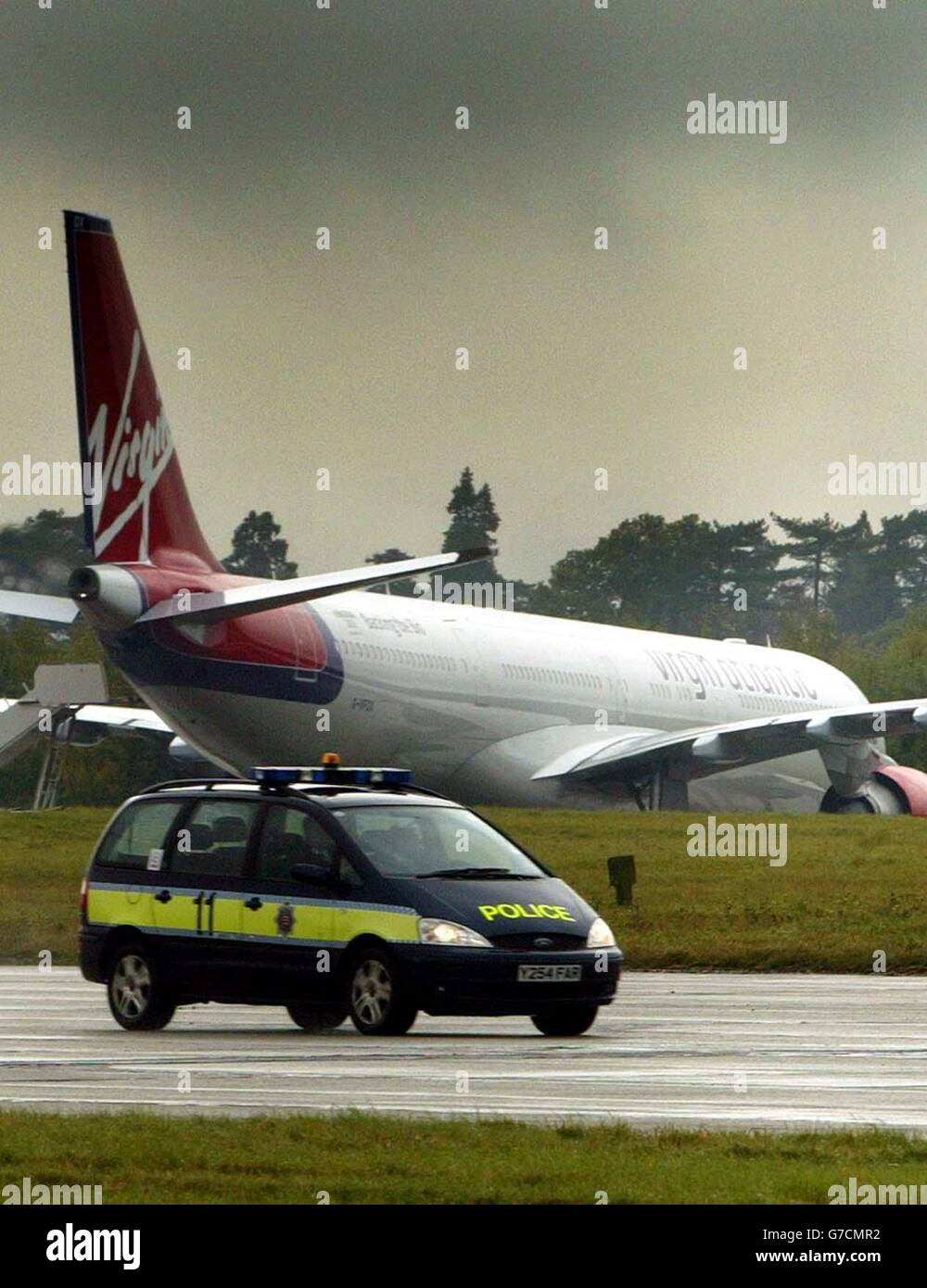 A police vehicle passes the Virgin Atlantic Airbus A340-600 which landed at Stansted airport in Essex, following a security alert. The plane was travelling from Hong Kong to London's Heathrow airport and carrying 214 passengers and 18 crew. Essex Police are investigating the incident. Stock Photo