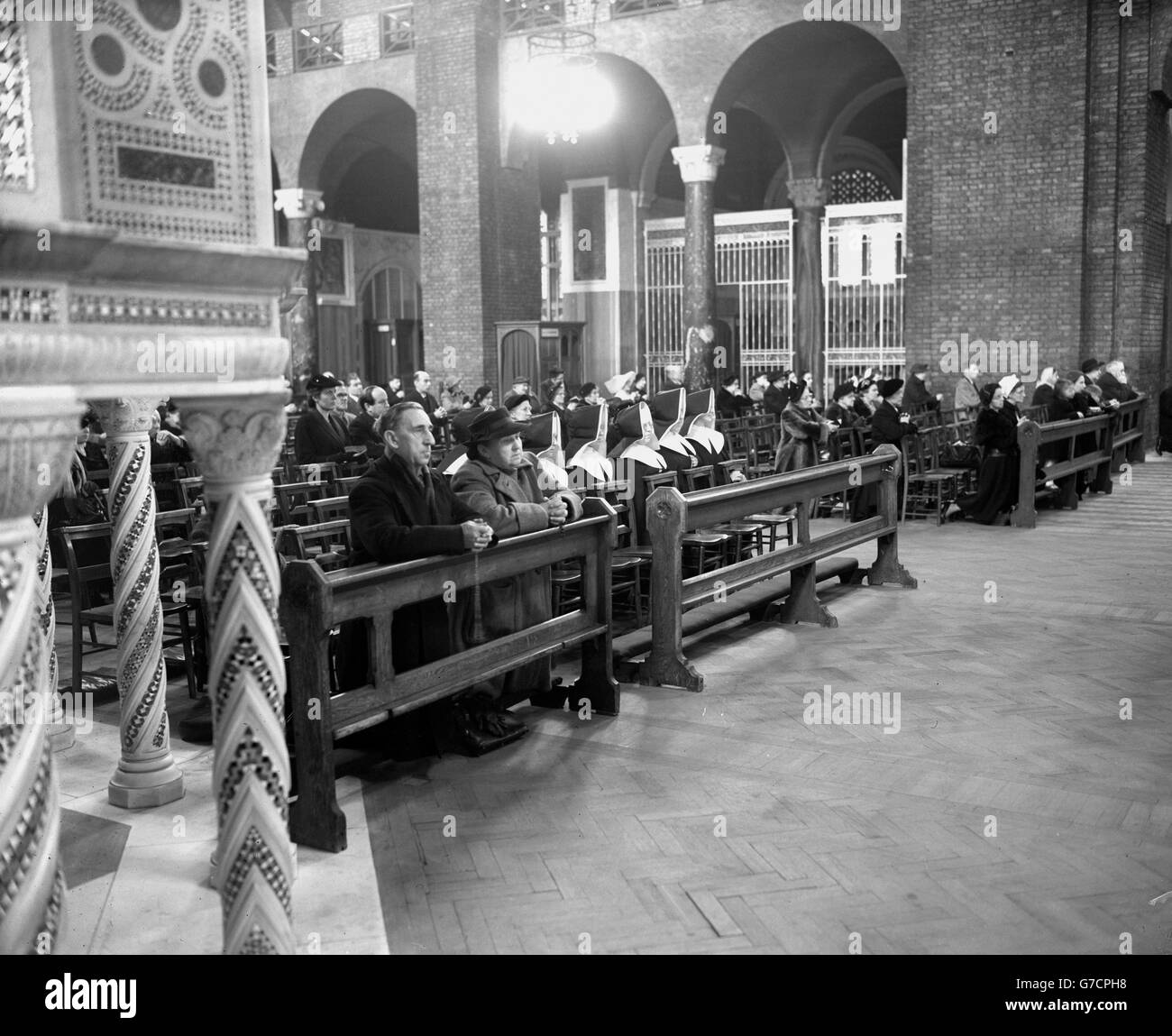 Roasaries in clasped hands, an elderly couple join with nuns and other Catholics in a Memorial Service for Queen Mary at Westminster Cathedral, London. Stock Photo