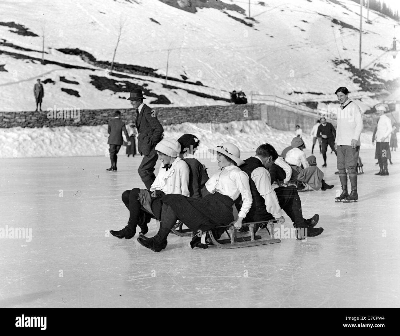 1913: Girls slide on a toboggan at an ice rink in Murren, Switzerland. Stock Photo
