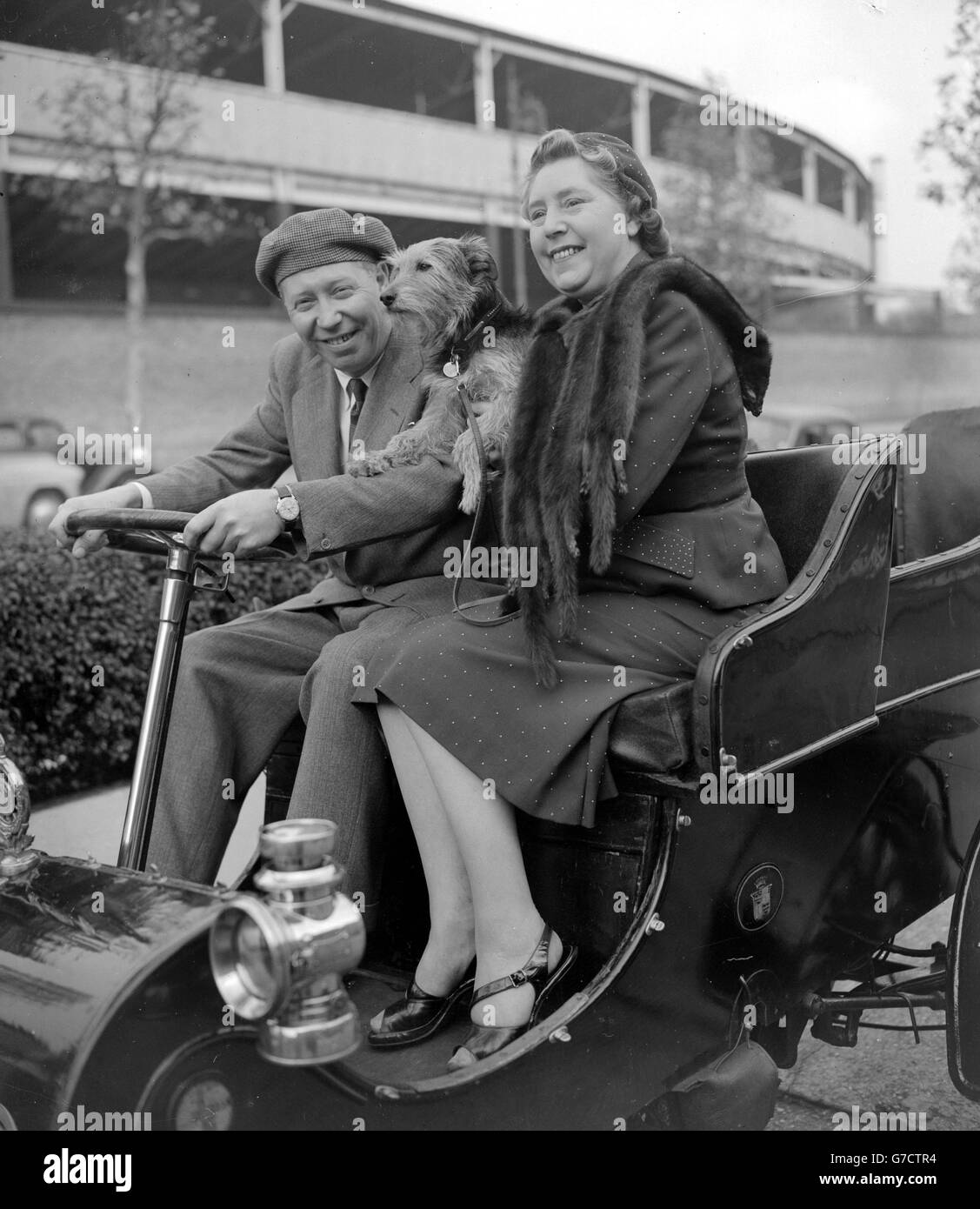 Variety star George Formby, his wife Beryl and their dog Punch, get a foretaste of the Veteran Car Rally as they take a practice run at St John's Wood, London, in the 1903 Cadillac owned by Mr F S Bennett. Formby and his wife will be passengers in the car when it competes in the 1953 Rally. Stock Photo