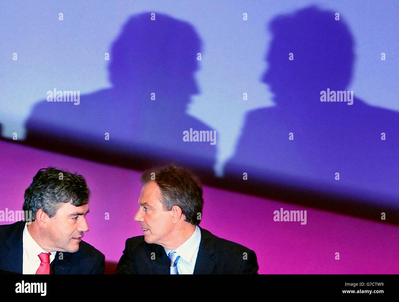 Tony Blair and Gordon Brown talk during Bono's speech to the Labour