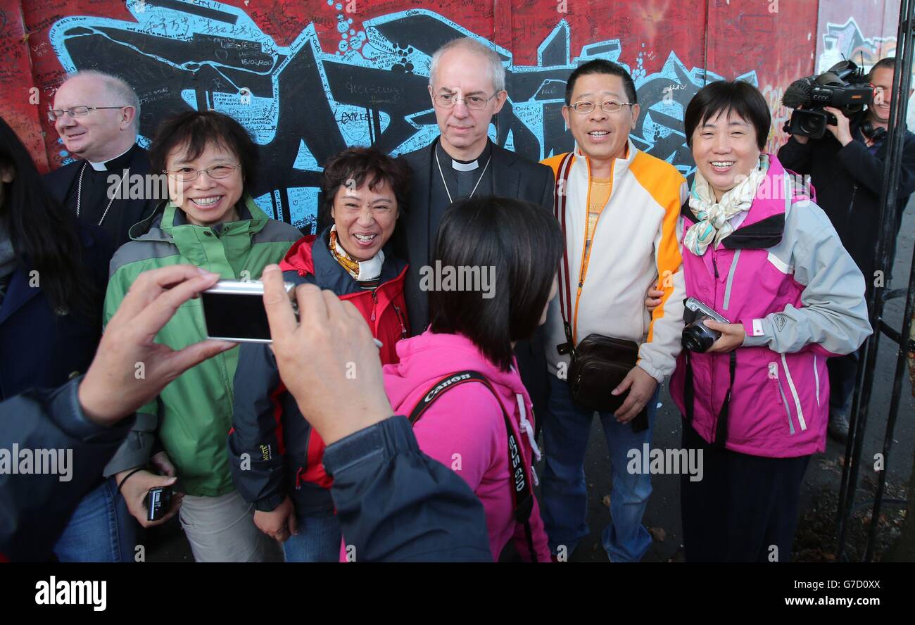 Archbishop of Canterbury Justin Welby meets a group Chinese tourists as he pays a visit a to the peace wall in Cupar Way, in west Belfast. Stock Photo