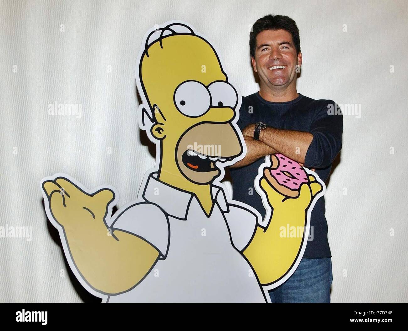 Simon Cowell poses with a cardboard cut-out of cartoon character Homer Simpson, as he arrives for the UK premiere screening of Smart and Smarter - a new episode of The Simpsons on Sky One - in which he stars, at the Rex Cinema and Bar, Rupert Street, central London. Stock Photo