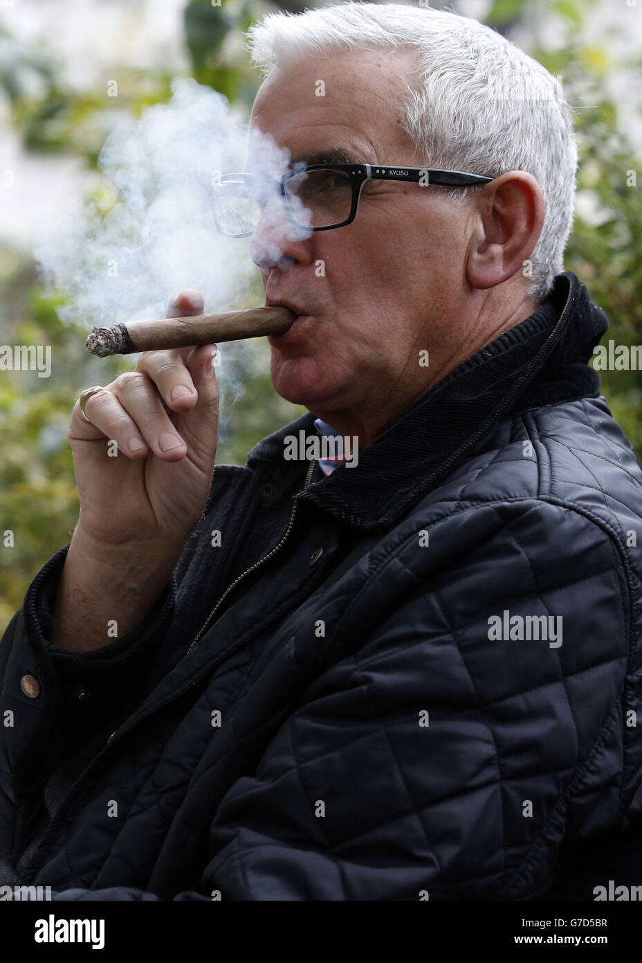 A man smokes a cigar in St. James' Park, London following the publication of the London Health Commission Report with a recommendation from a health panel that would make thousands of acres of parkland in London and landmarks including Trafalgar Square smoke-free zones. Stock Photo