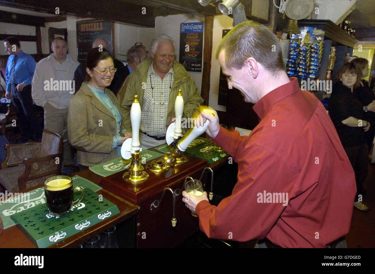 Landlord Guy Ayres pulls the first pint for customers Malcolm Grant and wife Alison at the The Cat Inn, in Enville, South Staffordshire, as the pub opens its doors on a Sunday for the first time in 300 years. The public house has been shut on a Sunday since a decree by the local landowner in the 18th century. Stock Photo