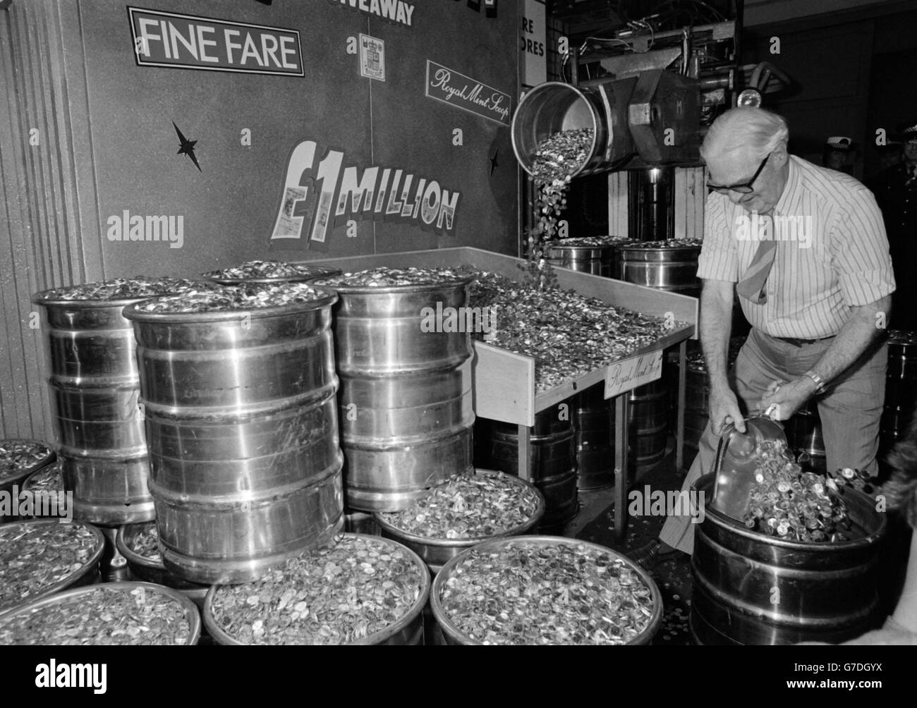 Retired bank manager Mr Bert Nicol, 69, from St Andrew's, Fife scooping 18,000 in freshley-minted pound coins at the Royal Mint in Mid-Glamorgan. Stock Photo