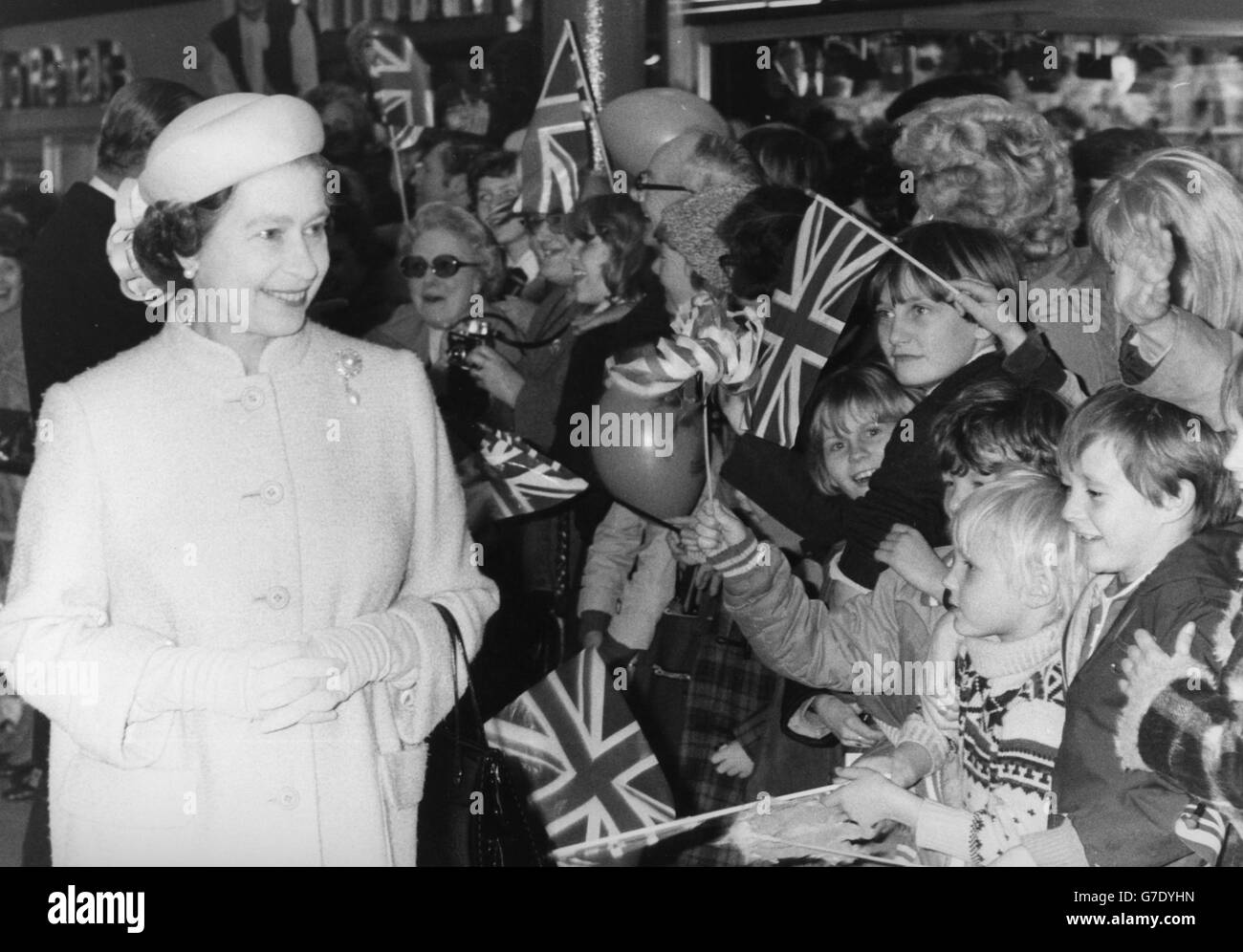 Queen Elizabeth II receives an enthusiastic welcome from flag-waving youngsters on her arrival in Warrington. Stock Photo