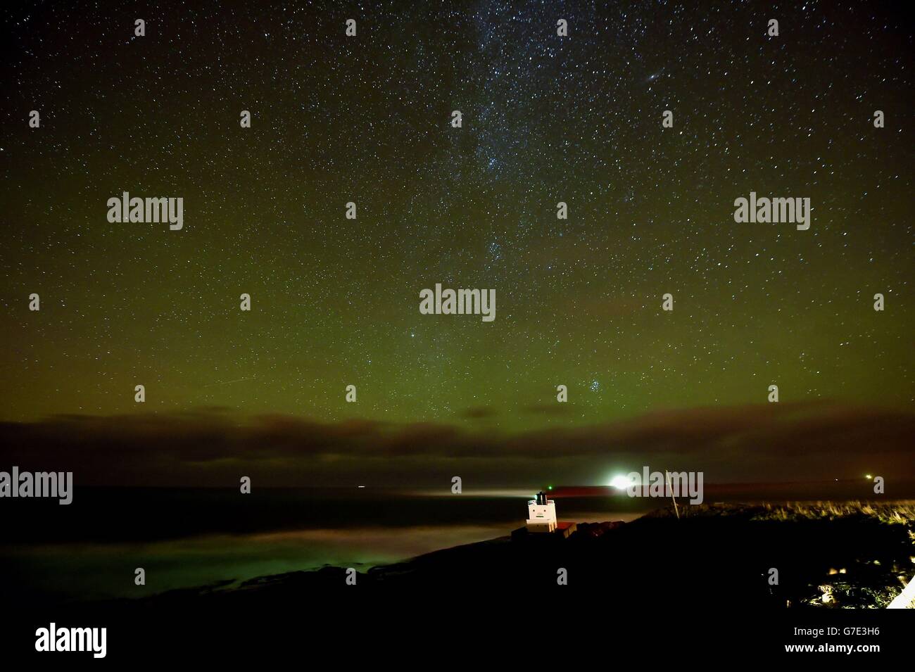 Editors note: Picture taken using a long exposure. An aurora is seen on the horizon behind Bamburgh Lighthouse in Northumberland. Stock Photo