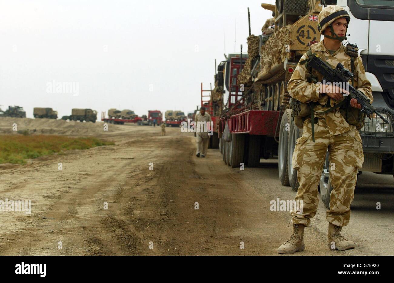 A British soldier from the 1st The Queen's Dragoon Guards walks alongside a British army convoy preparing to travel overnight, from Basra to join the Black Watch Battle group at Camp Dogwood, 20 miles south west of Baghdad. Stock Photo