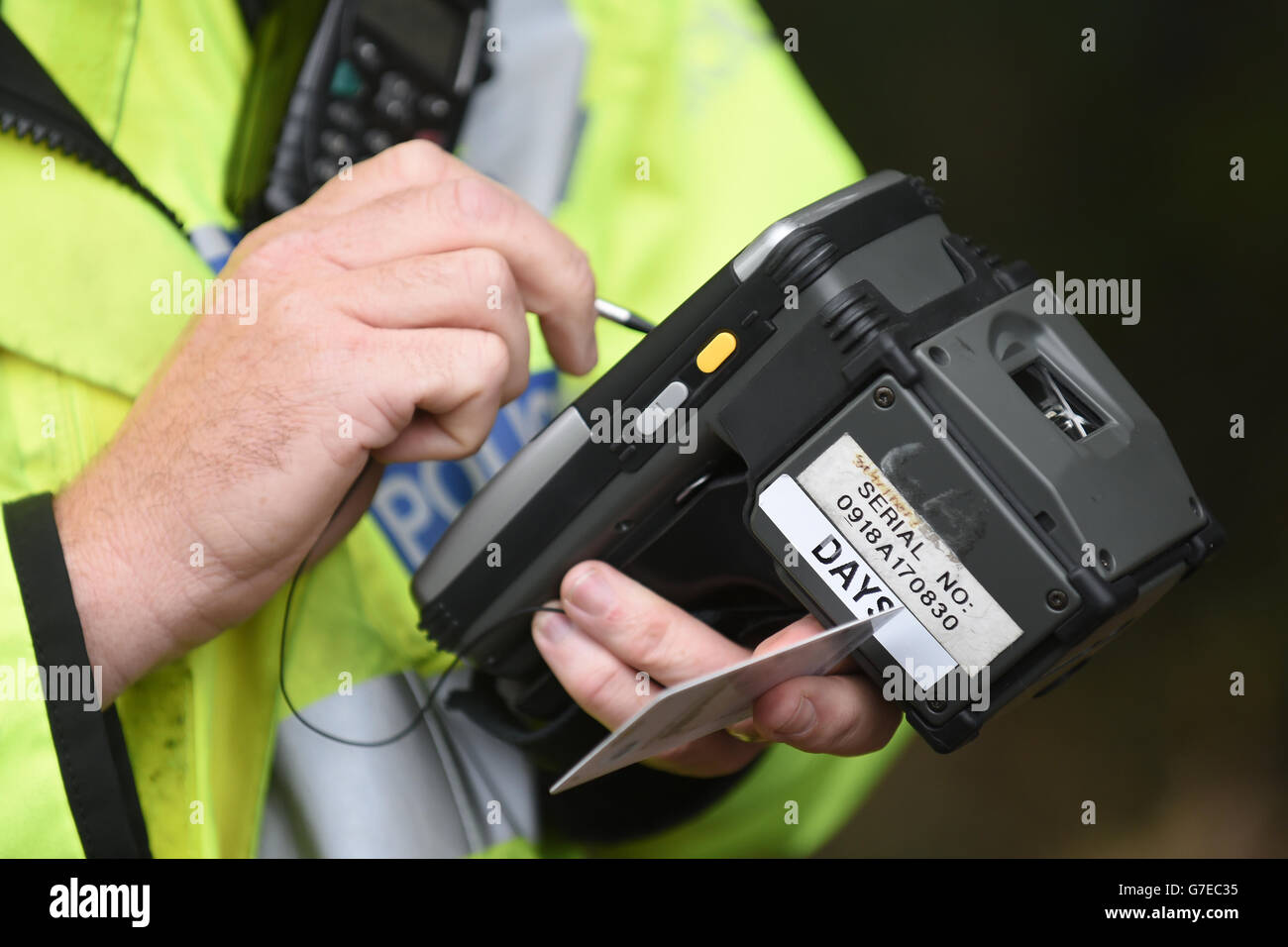 A police officer checks a drivers details on a mobile identification device Stock Photo