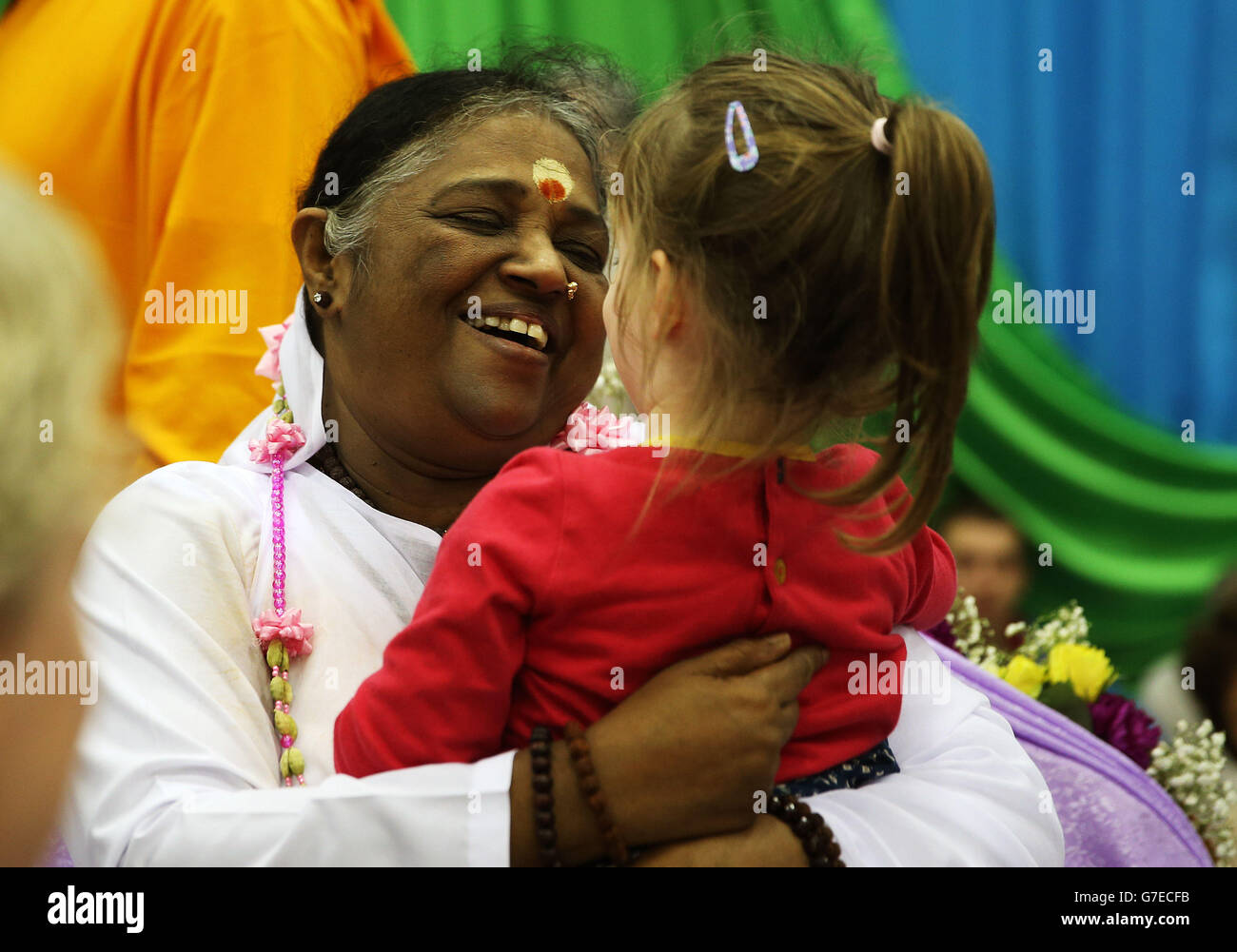Mata Amritanandmayi (Amma) embraces Clara Lally, three, during a two
