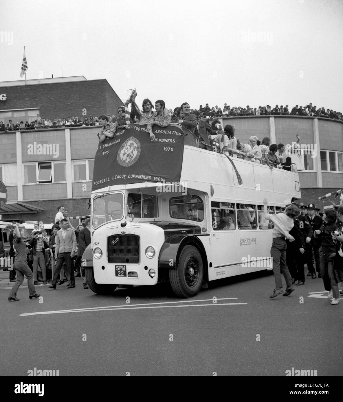 Alan Hudson holds aloft the European Cup Winners' Cup from an open-top bus as Chelsea are welcomed by hundreds of fans at Heathrow Airport on their return from Athens, where they beat Real Madrid to win the trophy. Chelsea's Alan Hudson holds the Cup, with (L-R) Peter Houseman, Marvin Hinton, Keith Weller and captain Ron Harris. Goalkeeper Peter Bonetti waves from a rear seat. Stock Photo