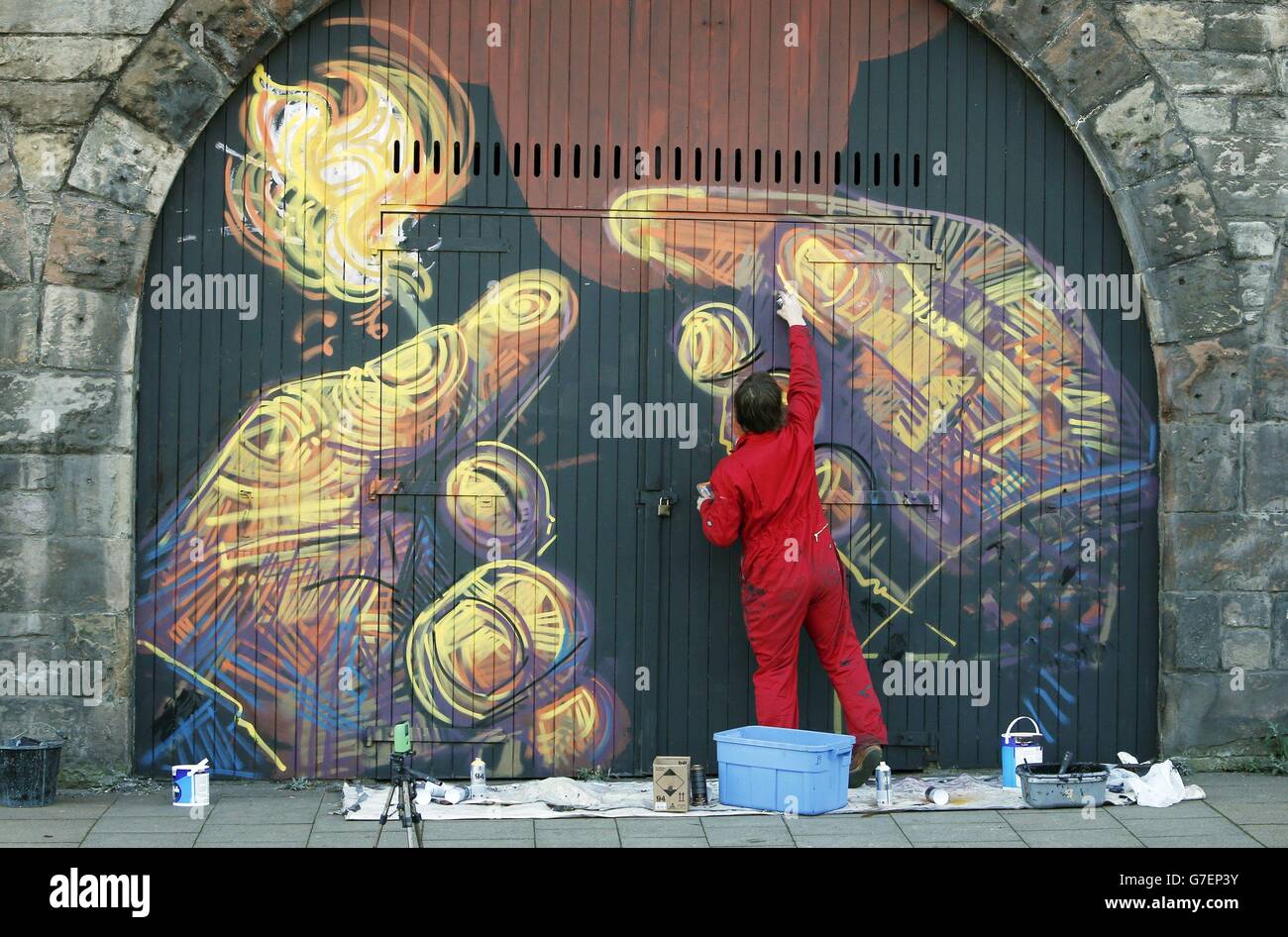 A graffiti artist puts the finishing touches to a piece at Scotland's largest street art project in the heart of Edinburgh's Old Town where series of ever-changing canvases will span almost half a kilometre. Stock Photo