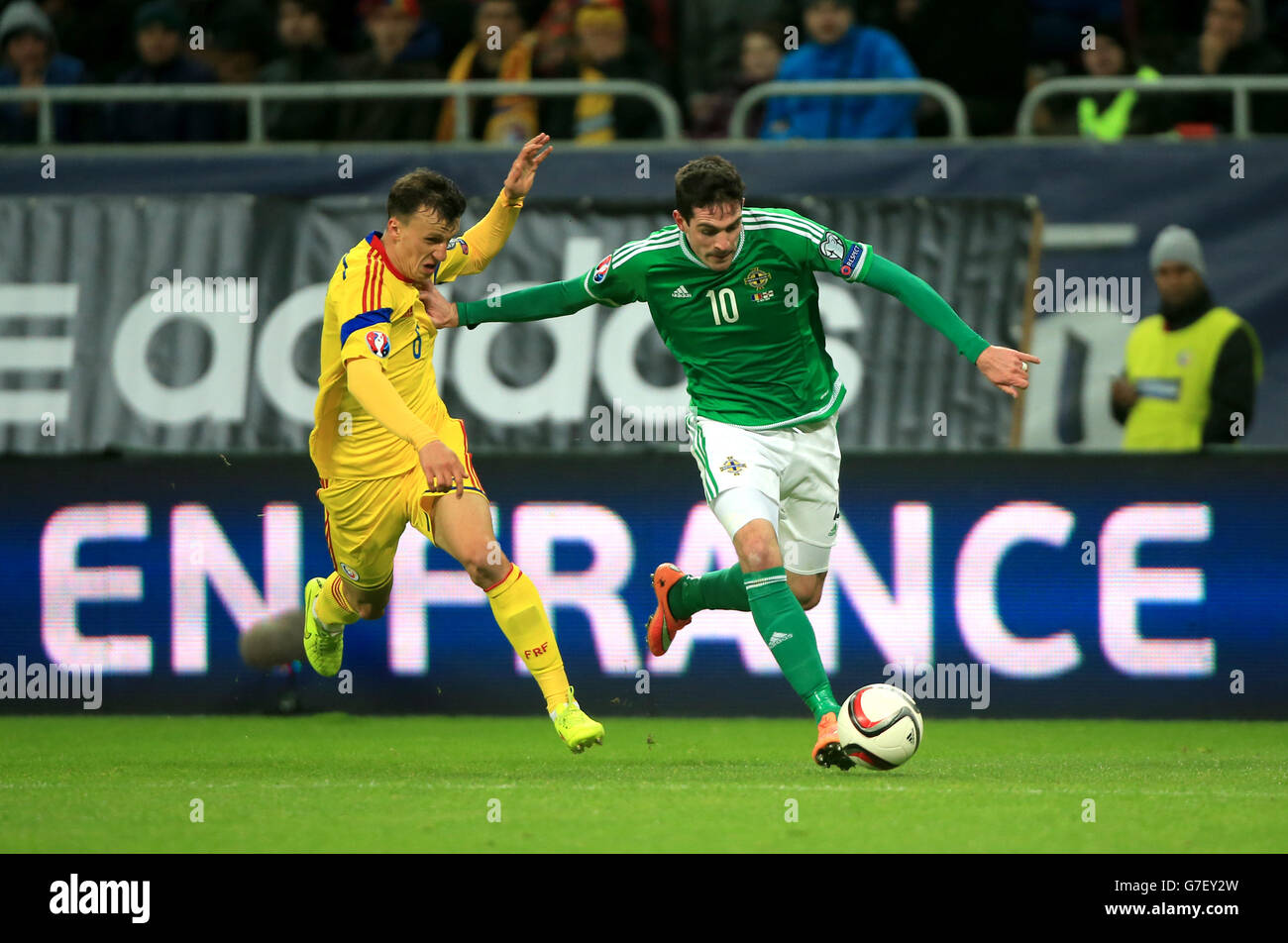 Northern Ireland's Kyle Lafferty (right) and Romania's Vlad Chiriches battle for the ball during the UEFA Euro 2016 qualifier at the Arena Nationala, Bucharest. Stock Photo
