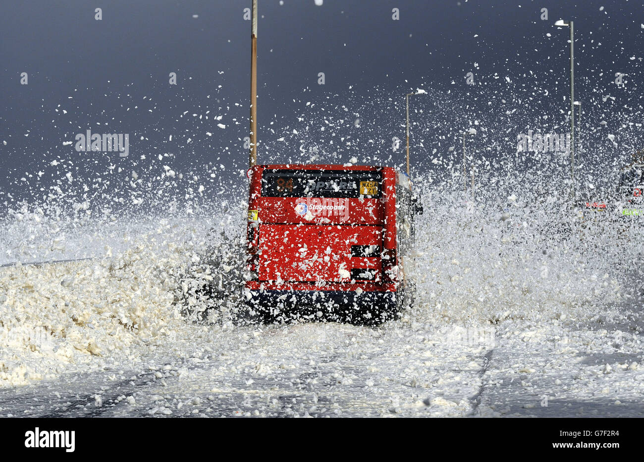 A bus drives through a blizzard of foam as gales and large waves hit the seafront at Cleveleys, near Blackpool, as the remnants of Hurricane Gonzalo blew into Britain, causing rush-hour travel misery for road, rail and air travellers. Stock Photo