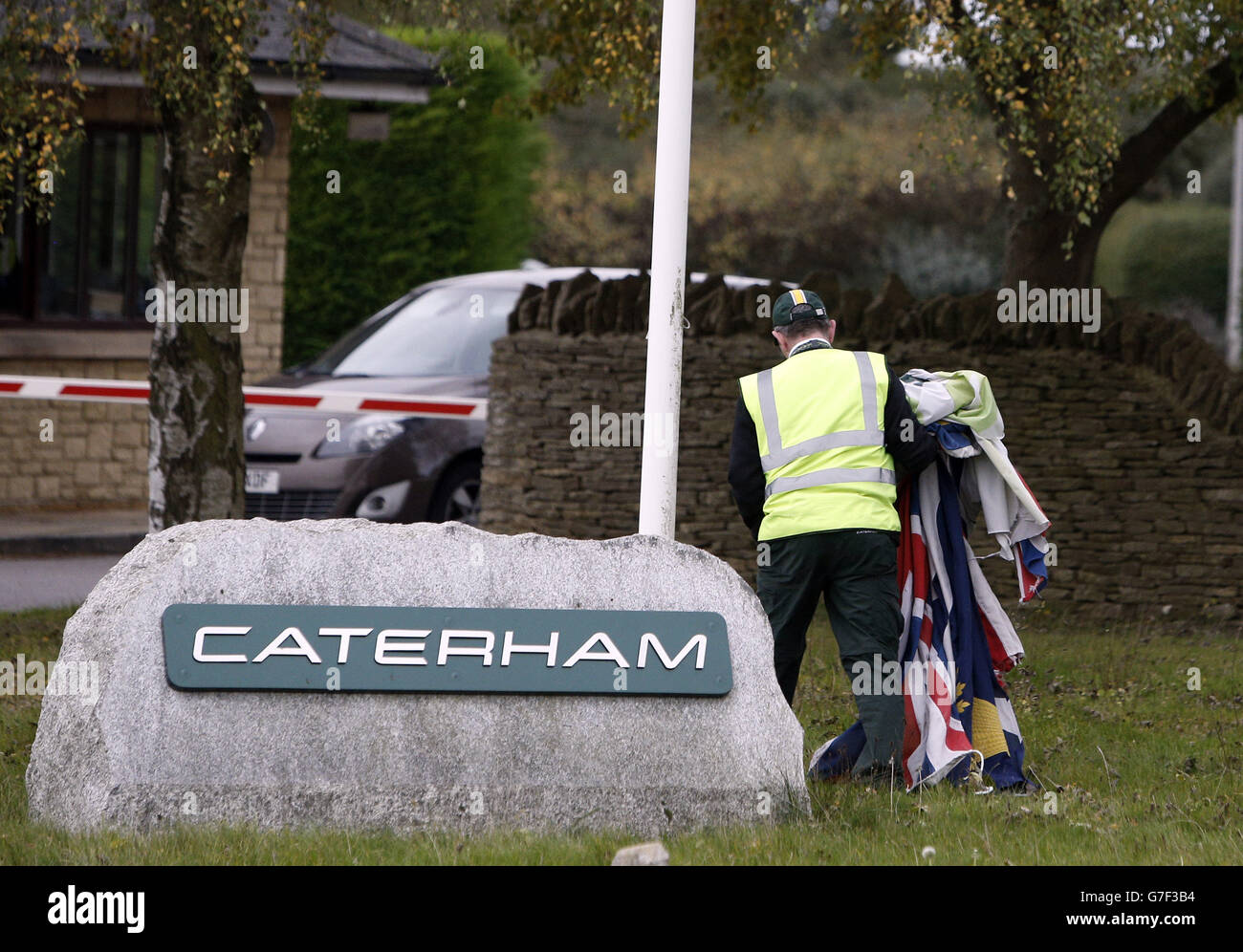 A Security guard removes the flags from the Caterham factory in Leafield, Oxfordshire. Stock Photo