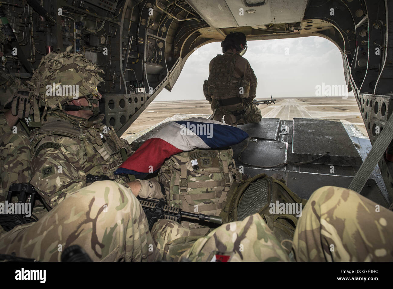 Wing Commander Matt Radnall, Officer Commanding 7 Force Protection Wing, sits with his carefully folded Union Flag on his Bergen as the very last British Chinook helicopter takes off from Camp Bastion, Helmand Province, Afghanistan, as UK and Coalition forces carry out their Tactical Withdrawal finally leaving the base, and handing it over to Afghan National Army. Stock Photo