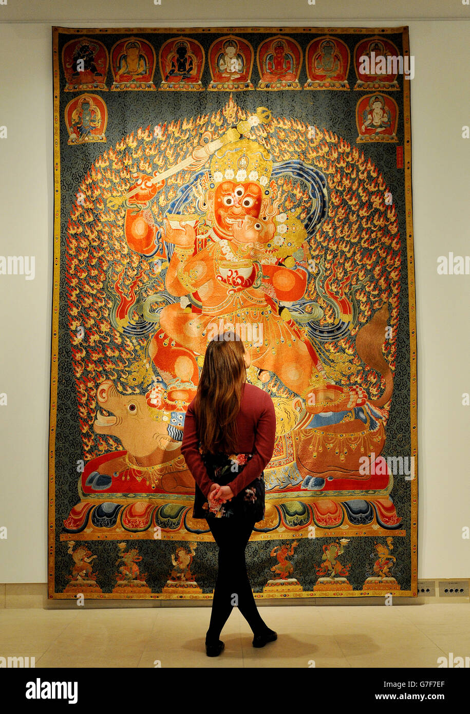 A Christie's employee looks at an embroidered imperial silk thangka from the Ming dynasty Yongle period (1402 - 1424) estimated at US $ 10,000,000 which measures over three metres tall and more than two wide, on show at Christie's in central London, as part of the touring highlights sale of Chinese Ceramics, Works of Art and Textiles which will take place in Hong Kong on November 26th, with further items being offered for sale in Paris and New York at later dates. Stock Photo