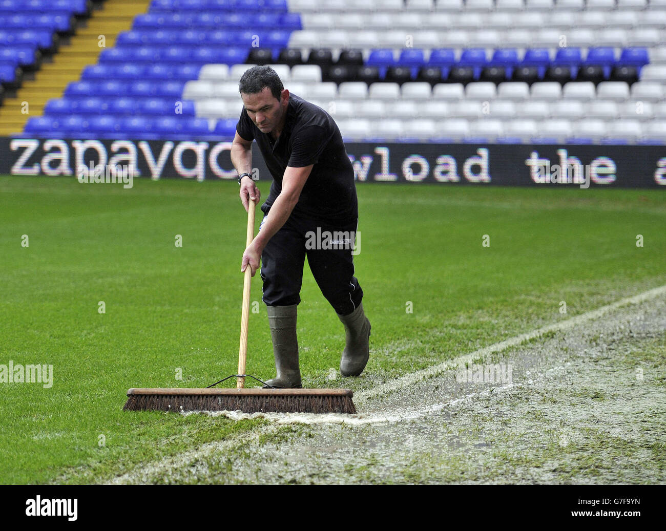 A groundsman brushes water from the pitch hires stock photography and