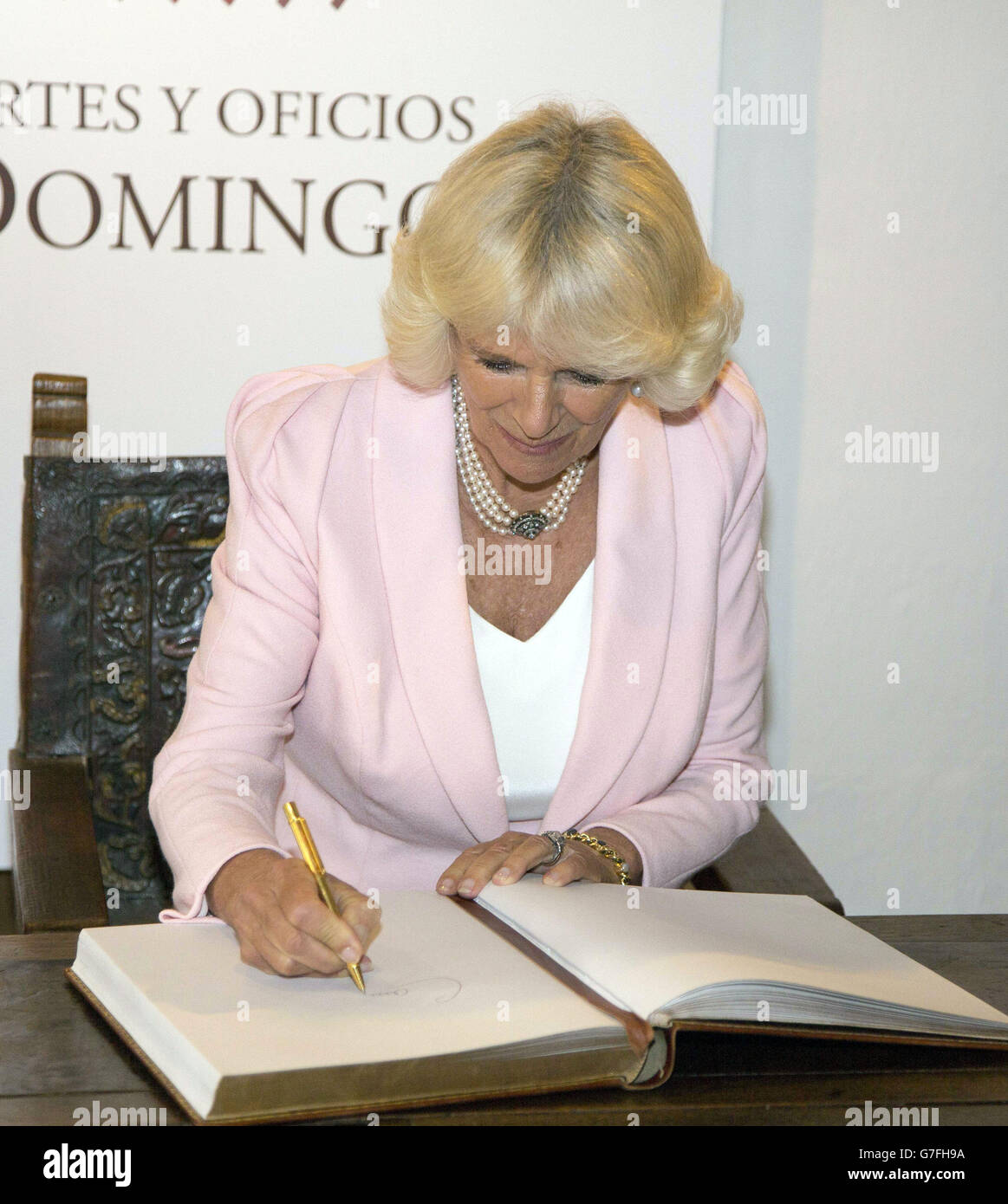 The Duchess of Cornwall signs the guestbook during a visit to the Euela de Artes Y Oficios, arts and crafts school in Bogota, Colombia. Stock Photo