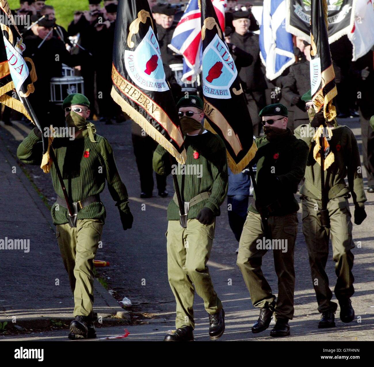 A masked Ulster Defence Association (UDA) colour party leads hundreds of its members to a Remembrance Day service in the Rathcoole estate, a loyalist stronghold on the outskirts of north Belfast. The UDA, Northern Ireland's largest loyalist paramilitary group, today pledged to end all violence and work towards complete disarmament. The announcement followed the decision of Northern Ireland Secretary Paul Murphy to recognise the UDA ceasefire. Stock Photo