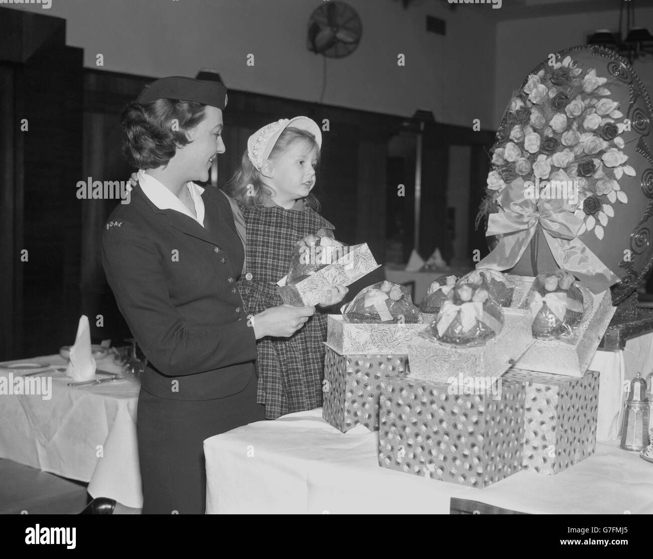 Five-year-old Holly Larsen, of Latrobe, Pennsylvania, USA, looks amazed as she compares the giant Easter egg on display at the BOAC Air Terminal, Victoria, London, with the smaller egg she is taking to her father in Bahrain. With Holly, who had just flown in by BOAC Comet jetliner from New York, is 24-year-old BOAC receptionist Joanne Symons, of Charles Street, London. Stock Photo