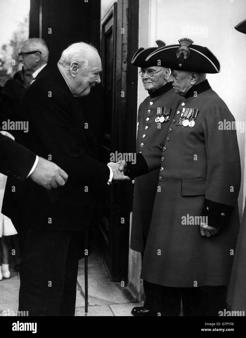 Sir Winston Churchill shakes hands with Chelsea pensioner Trooper Cooper, 74, outside the Royal Hospital Chapel in Chelsea. Churchill was attending the christening of his newest grandchild Rupert Christopher Soames. Stock Photo