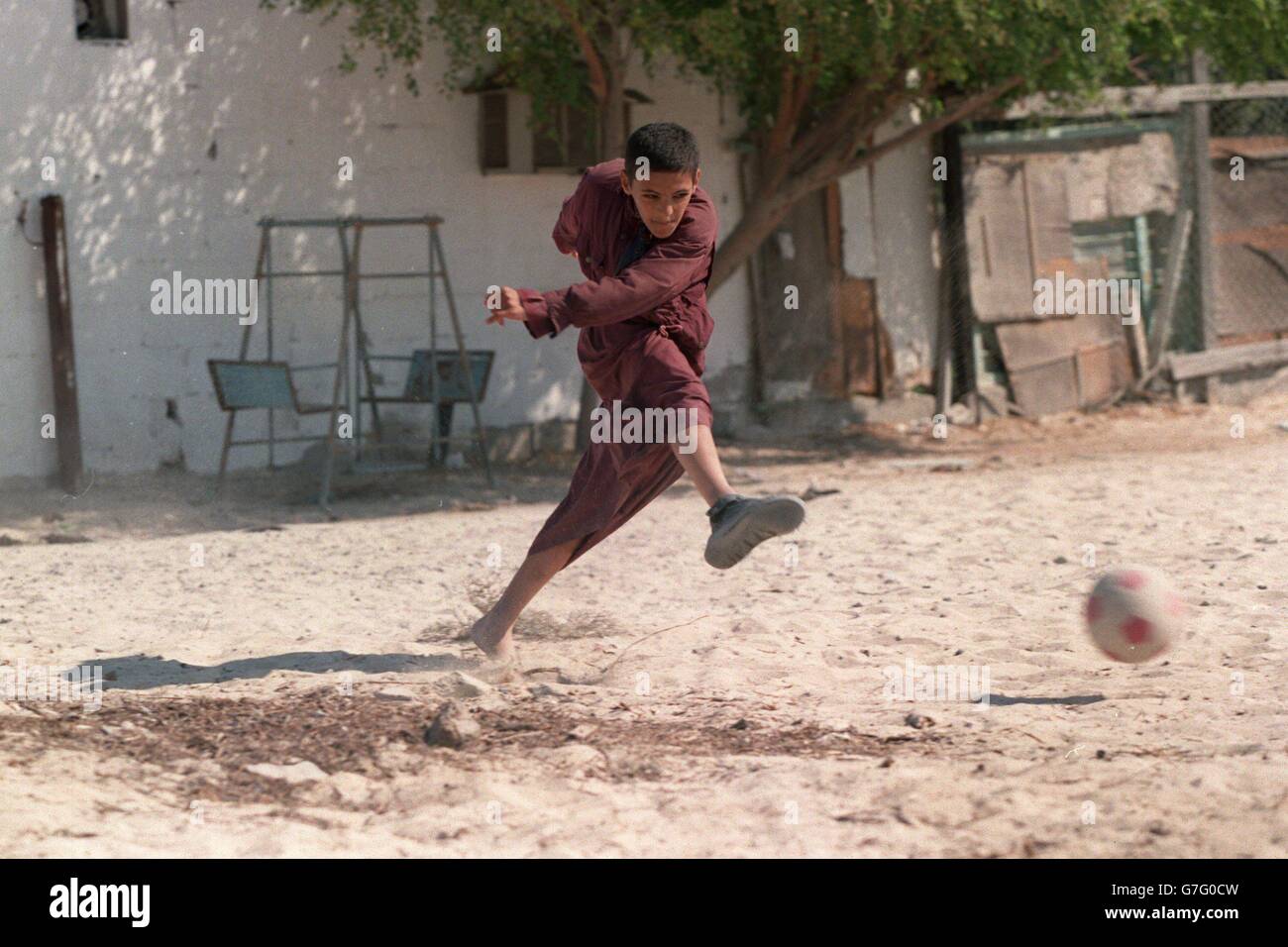 A young boy playing football in the sand outside his house in Dubai, UAE Stock Photo Alamy