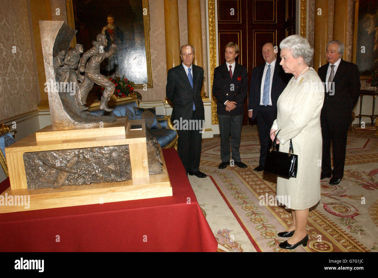 Queen Elizabeth II, at Buckingham Palace, with a maquette of the Battle of Britain Monument, which will honour the airmen who fought under RAF Fighter Command in the battle between July and October 1940. The maquette was presented by, from left to right, the Chairman of the Battle of Britain Monument Committee, Lord Tebbit, sculptor Paul Day, founder of the Battle of Britain Historical Society, Bill Bond and Maurice Djanogly, Deputy Chairman of the committee Stock Photo