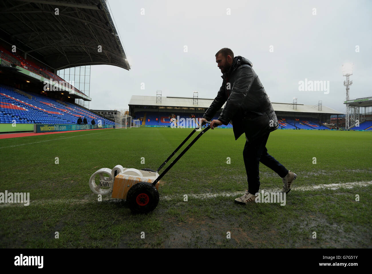 Groundsmen tend to the pitch in heavy rain before the match at Selhurst