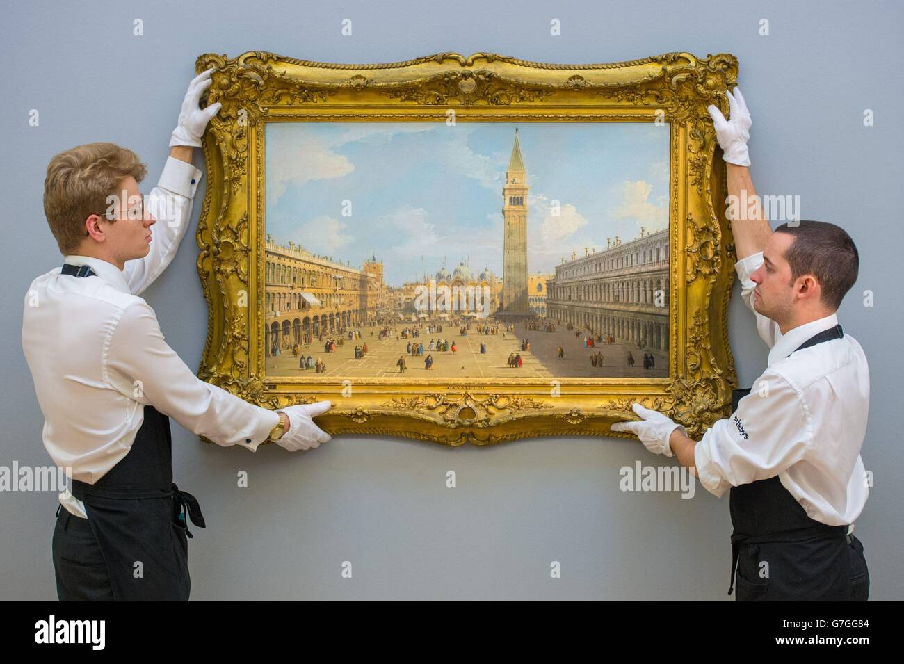 Sotheby's employees with Venice, the Piazza San Marco looking east towards the Basilica by Canaletto at Sotheby's gallery, in Mayfair, London, which is part of their Old Master &amp; British Paintings Evening Sale. Stock Photo