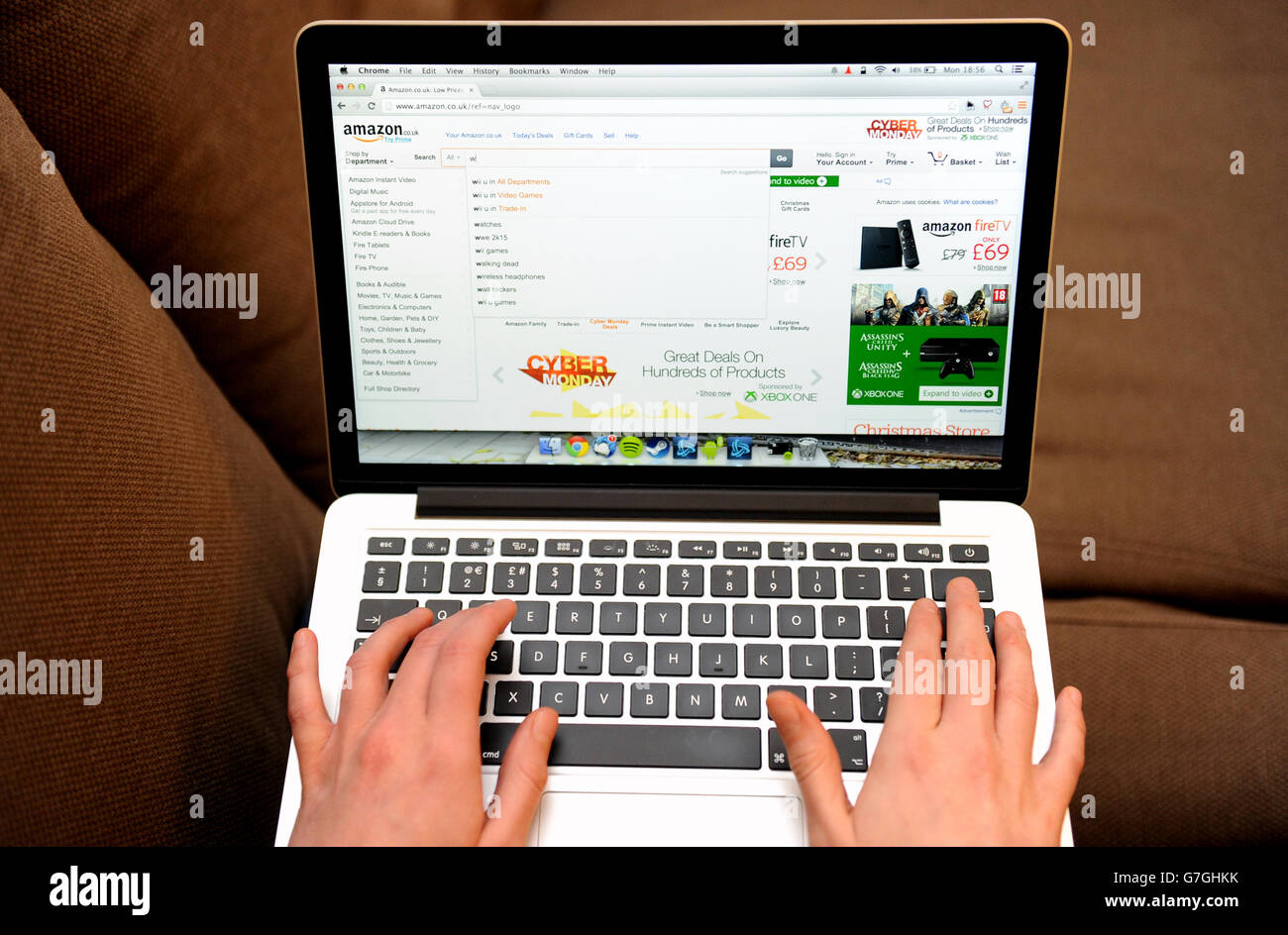 A woman uses a laptop to browse the Amazon website Stock Photo