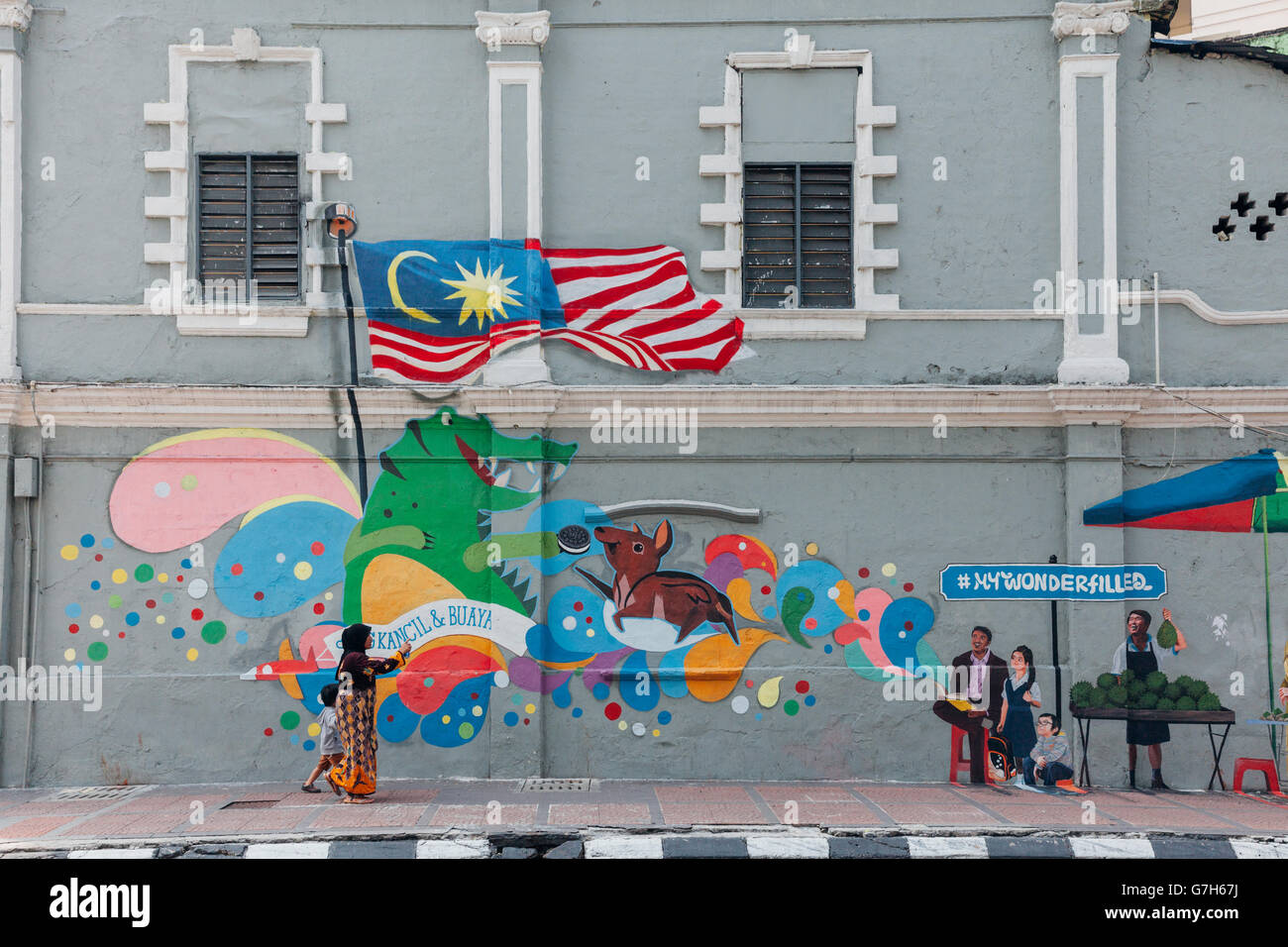 Woman in traditional muslim clothes shows street art to her son, Kuala Lumpur, Malaysia Stock Photo