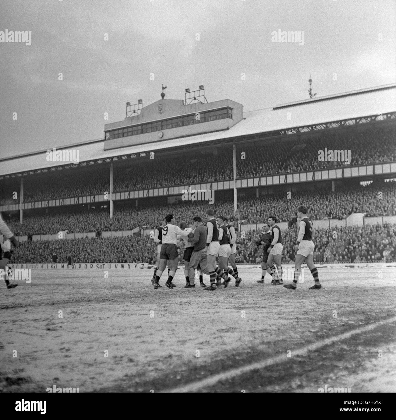 Referee R.T.E. Langdale (third from right) closes in on a group of players during a moment of tension in the FA Cup third round tie in the snow at White Hart Lane. According to an unnamed eyewitness, Tottenham Hotspur outside-left Terry Dyson (third from left) ruffled Burnley players because of persistently trying to kick the ball while it was still in the grasp of Burnley goalkeeper Adam Blacklaw (fourth from left). Emotions ran high, but it didn't help Spursas they were beaten 3-0 by Burnley. Stock Photo