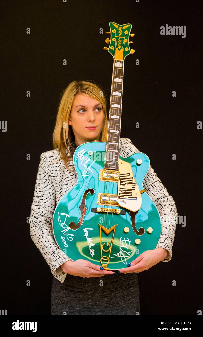A Christie's employee holds a customised Gretsch Irish Falcon guitar once owned by Bono and signed by all four members of U2, valued at &Acirc;&pound;120,000 to &Acirc;&pound;180,000, part of Christie's 20/21 Pop Culture Sale on 16th December 2014. Stock Photo