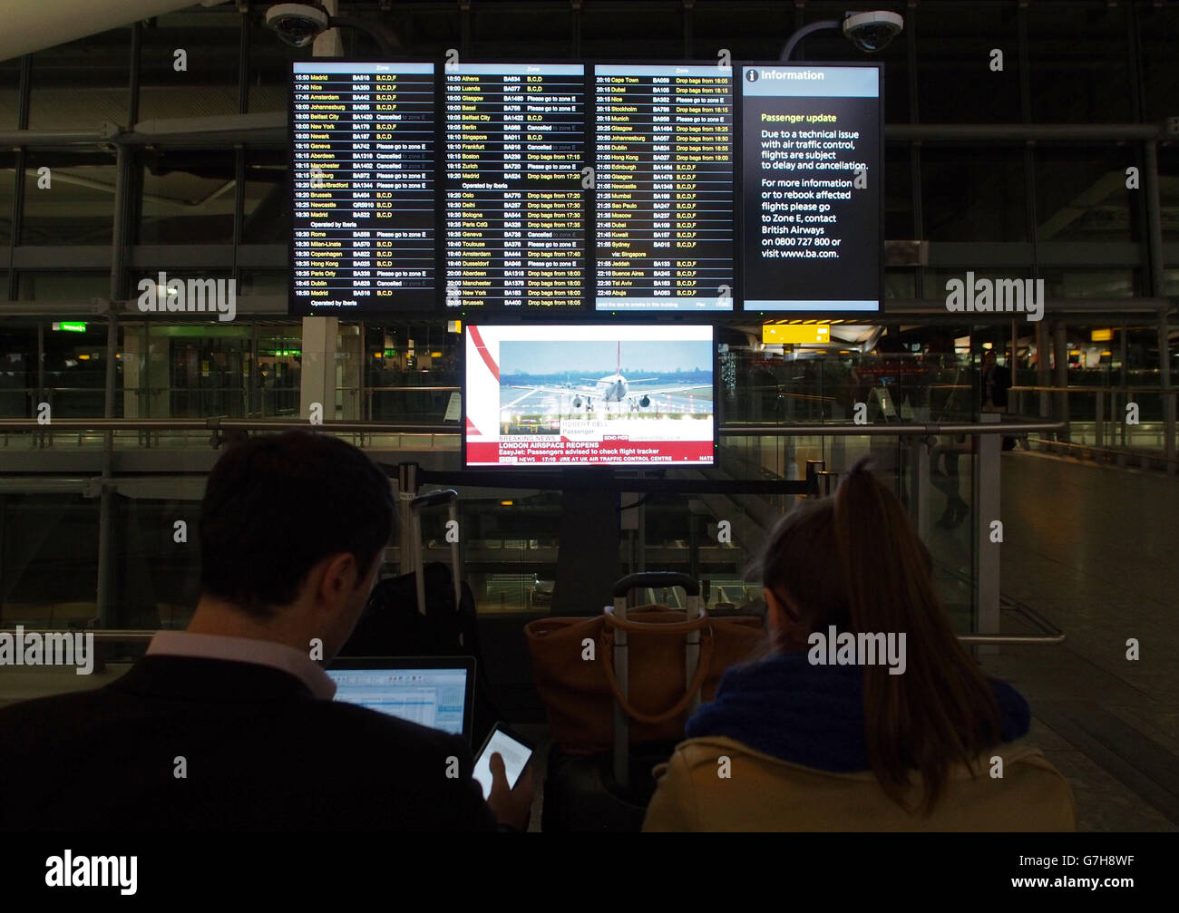 People watch an information board at Terminal 5 of Heathrow Airport as ...